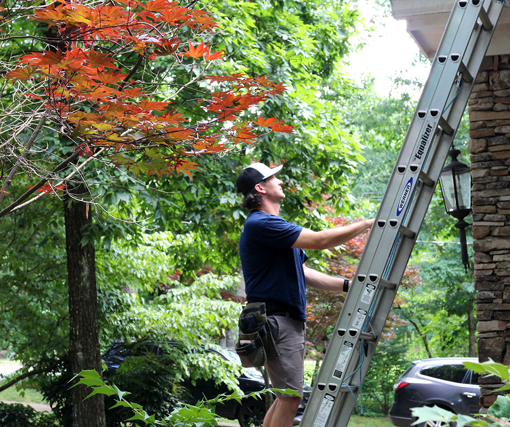 Crawford Parish, one of our certified home inspectors, using a ladder to access the roof of a house 